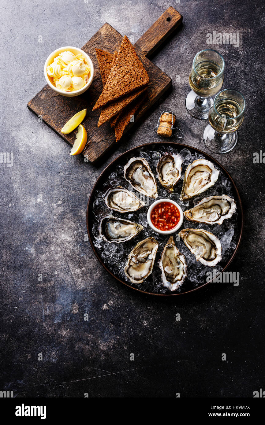 Abra las ostras con pan y mantequilla y champagne en la textura del fondo oscuro espacio de copia Foto de stock