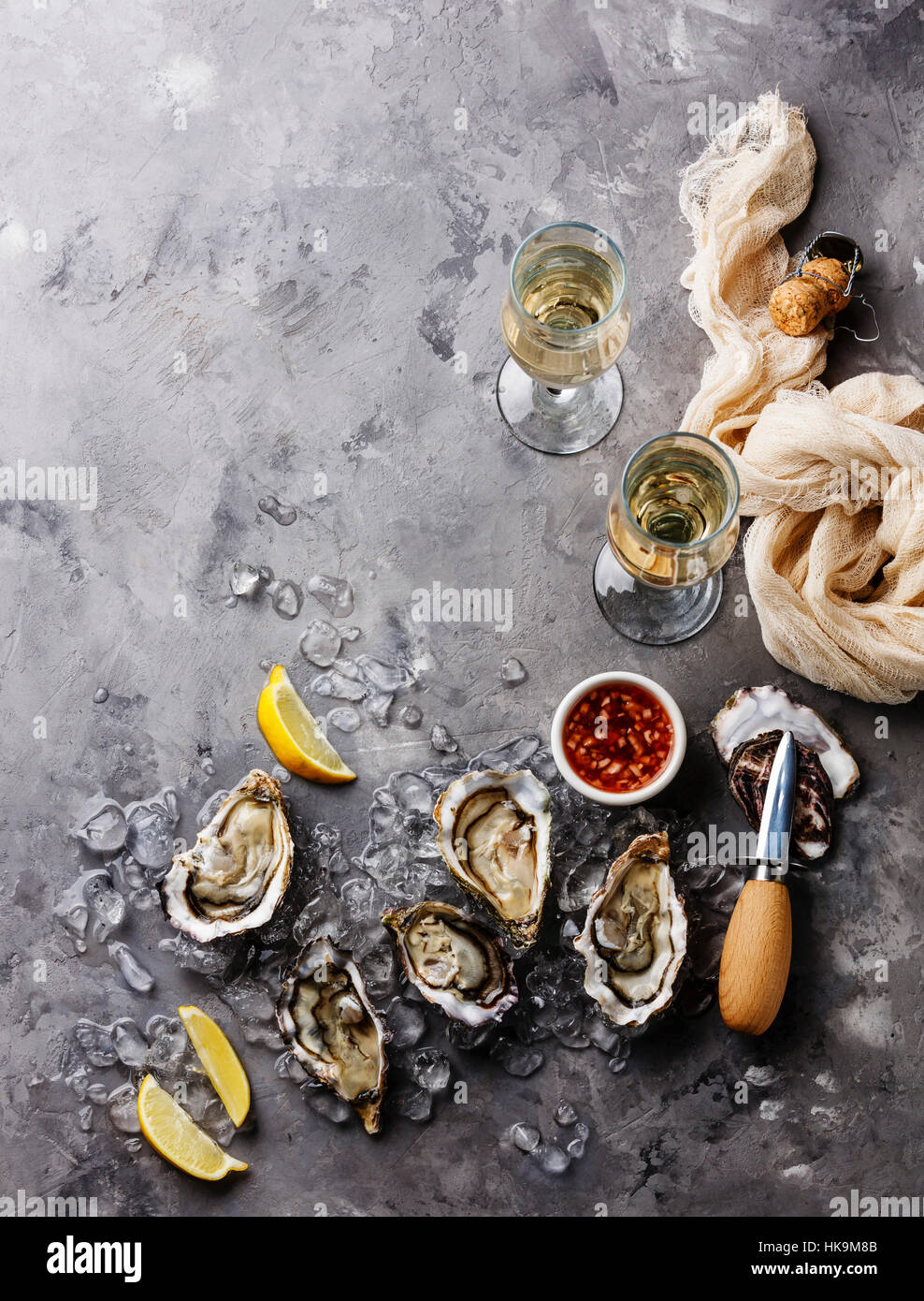 Abrir las ostras con la salsa y champagne en la textura del fondo de cemento gris espacio de copia Foto de stock