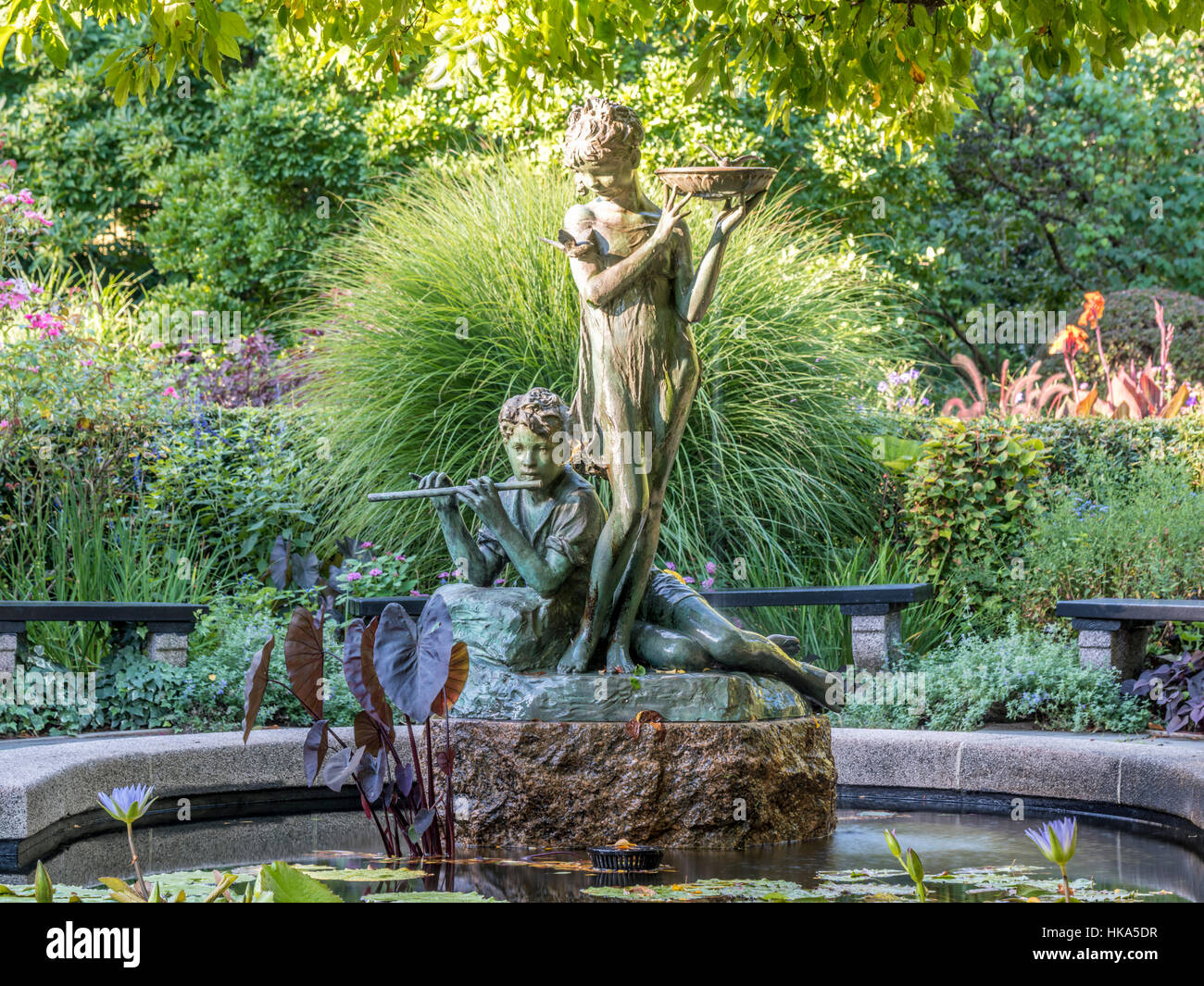 Fuente Burnett el Jardín Secreto de la escultura se encuentra en el borde de una pequeña piscina de hormigón que ofrece una gran variedad de lirios de agua. Foto de stock