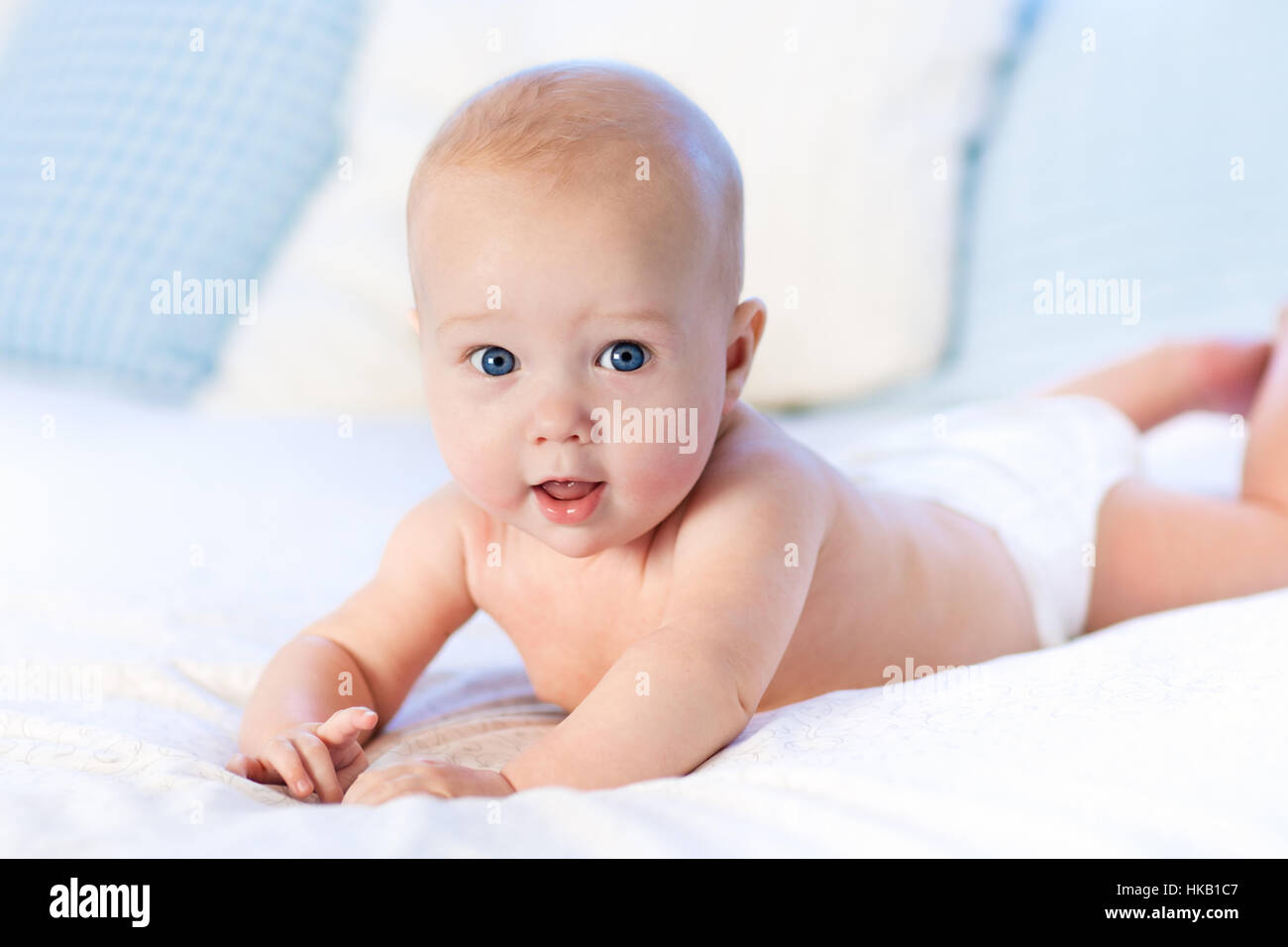 Baby Boy vistiendo pañal en blanco dormitorios soleados. Recién nacido descansando en la cama. Guardería para niños. Ropa de cama para niños. Foto de stock
