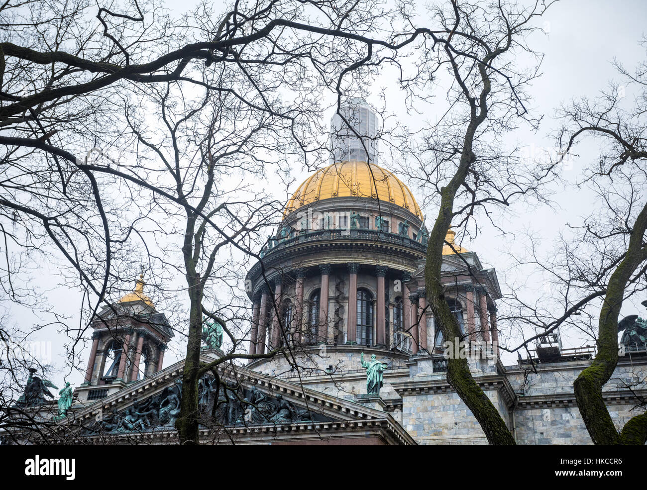 La famosa catedral de San Isaac y viejos árboles de roble en el espectacular cielo gris en San Petersburgo, Rusia Foto de stock
