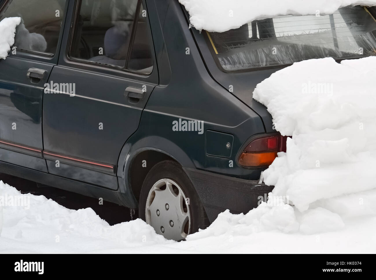 Coche aparcado bajo la nieve en un frío día de invierno Foto de stock