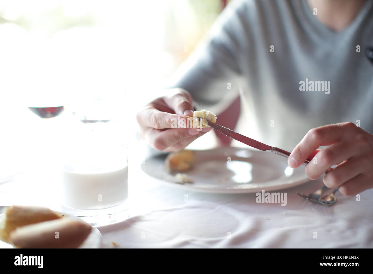 Hombre comiendo comida en mesa de restaurante. El pan, las manos, la placa, alimentos bebidas. Foto de stock