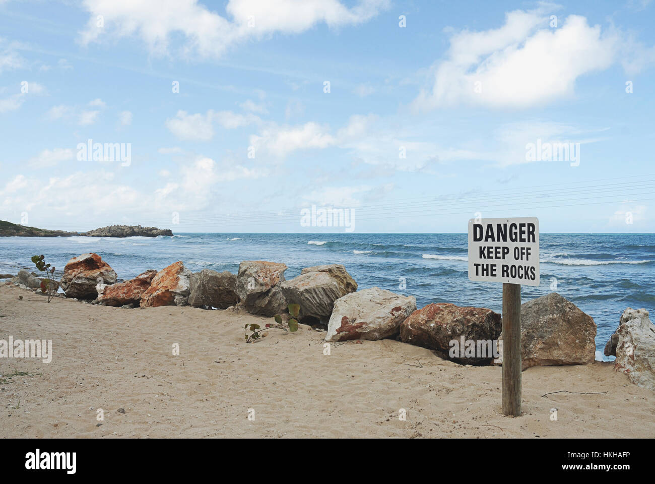 Firmar en la playa con el peligro de mantener las rocas Foto de stock