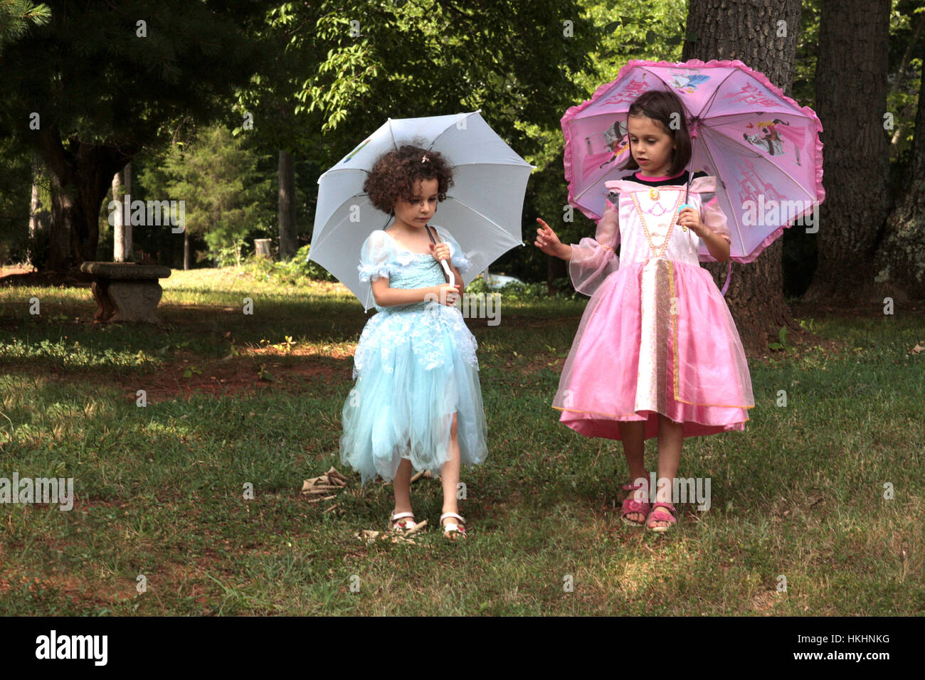 Dos niñas se visten con trajes de princesa caminando con sombrillas; fingen  jugar Fotografía de stock - Alamy