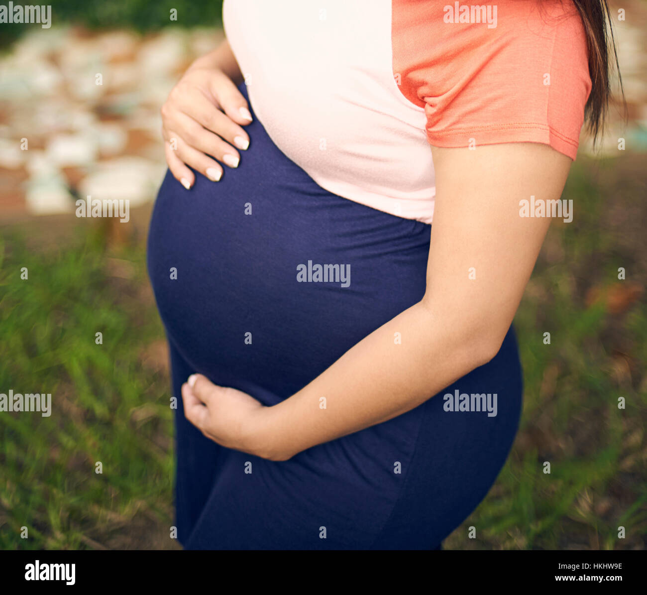 Mujer embarazada en el jardín verde con la mano en la parte superior Foto de stock