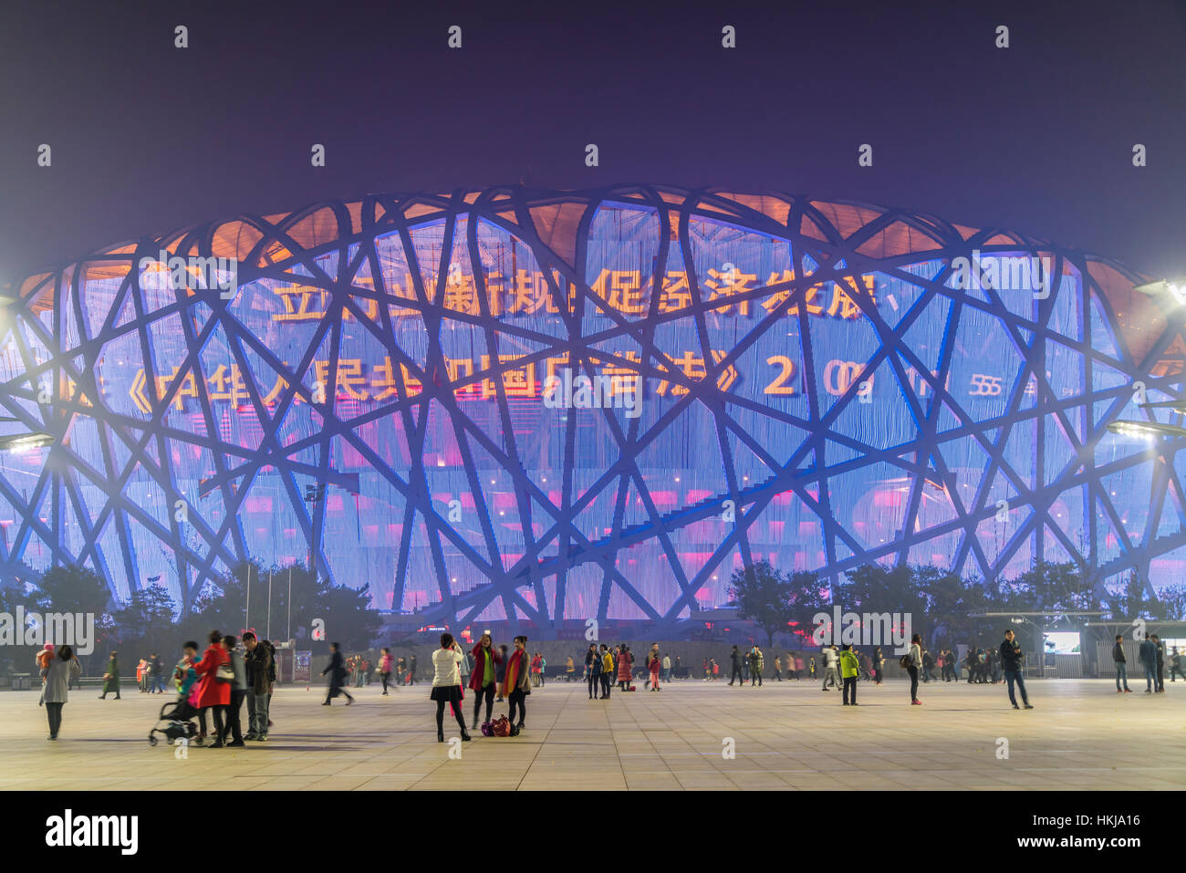 La gente en la plaza al frente del Estadio Nacional iluminado en el Parque Olímpico, al anochecer, Beijing, China Foto de stock