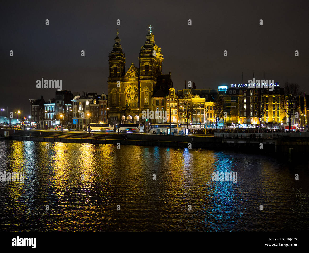 Hermosa noche en Amsterdam. Iluminación de edificios cerca del agua en el canal Foto de stock