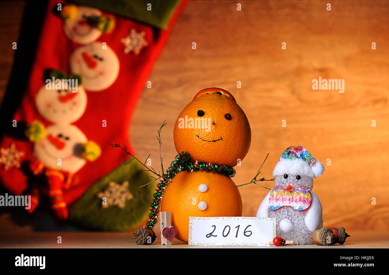 Decoración naranja muñeco de nieve sobre la mesa de madera con calcetines en la espalda Foto de stock