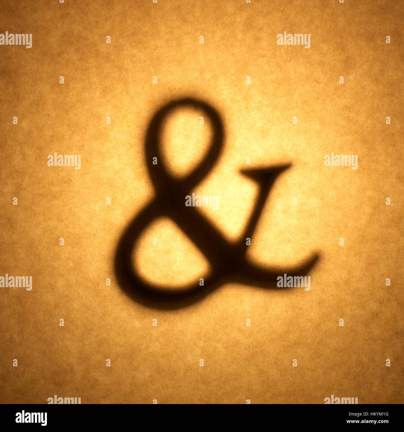 Silueta retroiluminado de ampersand forma recortada contra tono marrón de papel con manchas de resalte. Foto de stock