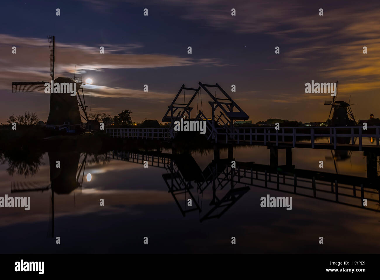 Kinderdijk en Holanda con molinos de viento y el puente levadizo de noche con luna llena. Foto de stock