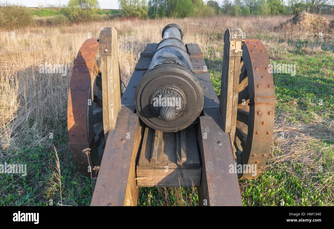 Viejo cañón con ruedas de madera en el campo Foto de stock