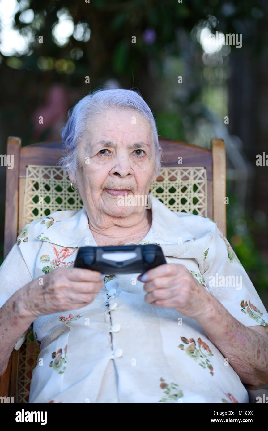 La abuela la celebración de joystick y jugar a videojuegos en estacionamiento Foto de stock
