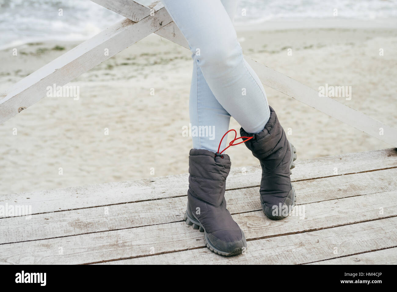 Los pies femeninos en blue jeans y botas deportivas de pie sobre una  plataforma de madera sobre la playa en otoño Fotografía de stock - Alamy