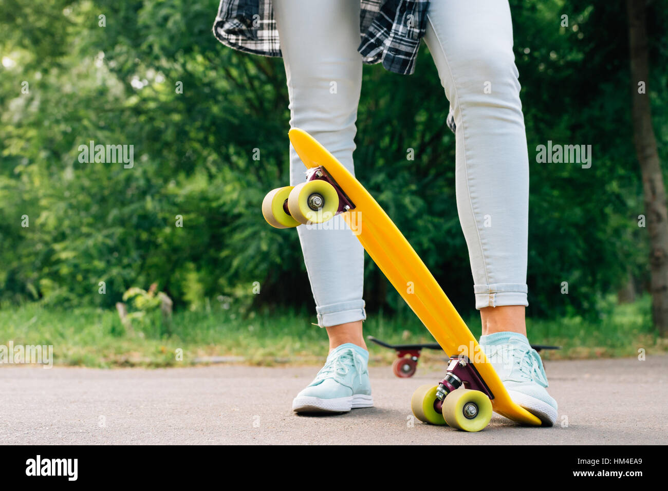 Las piernas de las mujeres en jeans y zapatillas sobre amarillo closeup  monopatín Fotografía de stock - Alamy