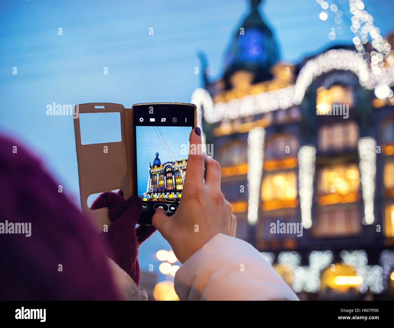 Mujer toma fotografías del libro a casa Zinger edificio por su Smartphone en San Petersburgo Foto de stock