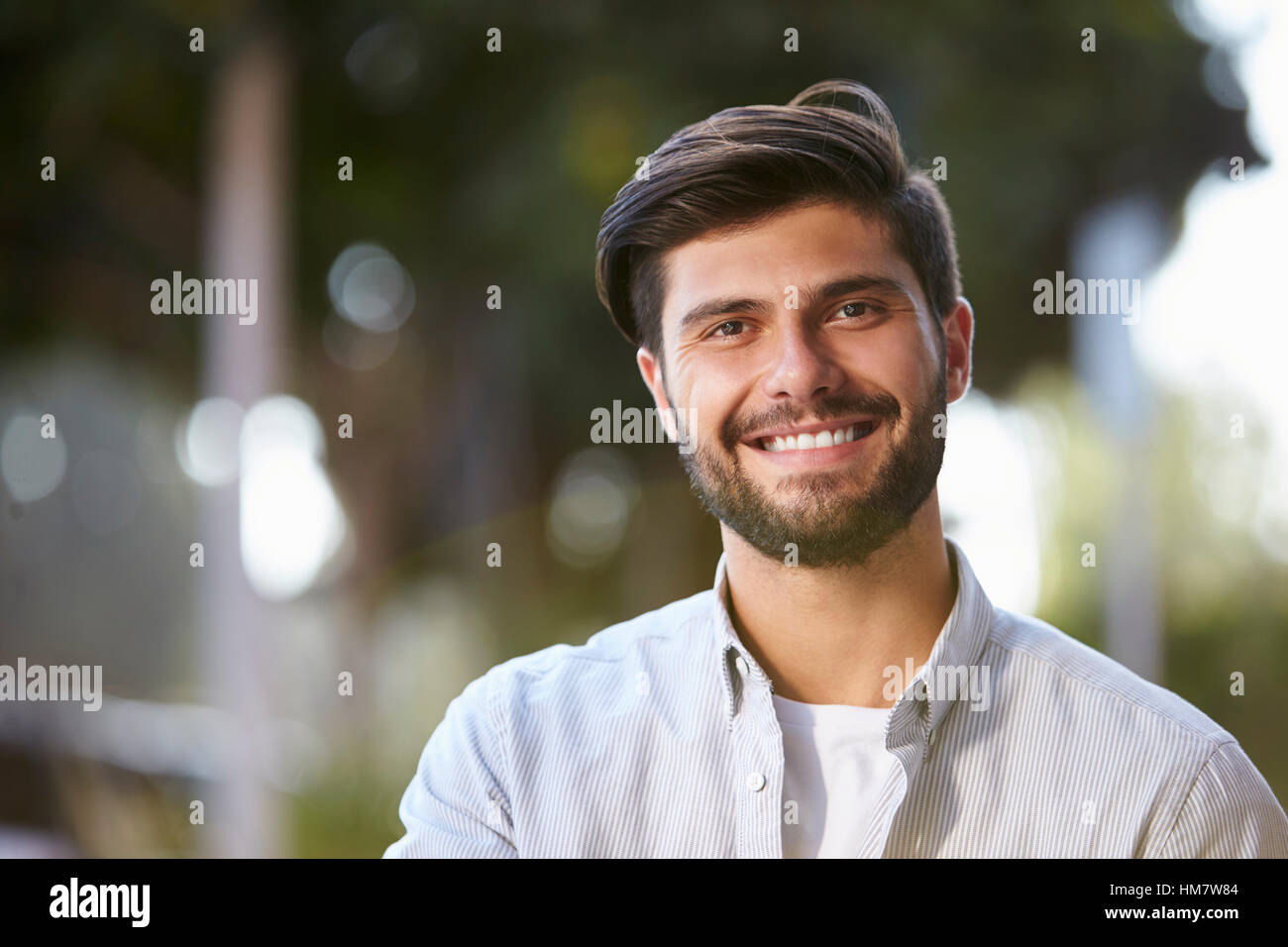 Sonriente joven barbudo sentado afuera, Retrato Foto de stock