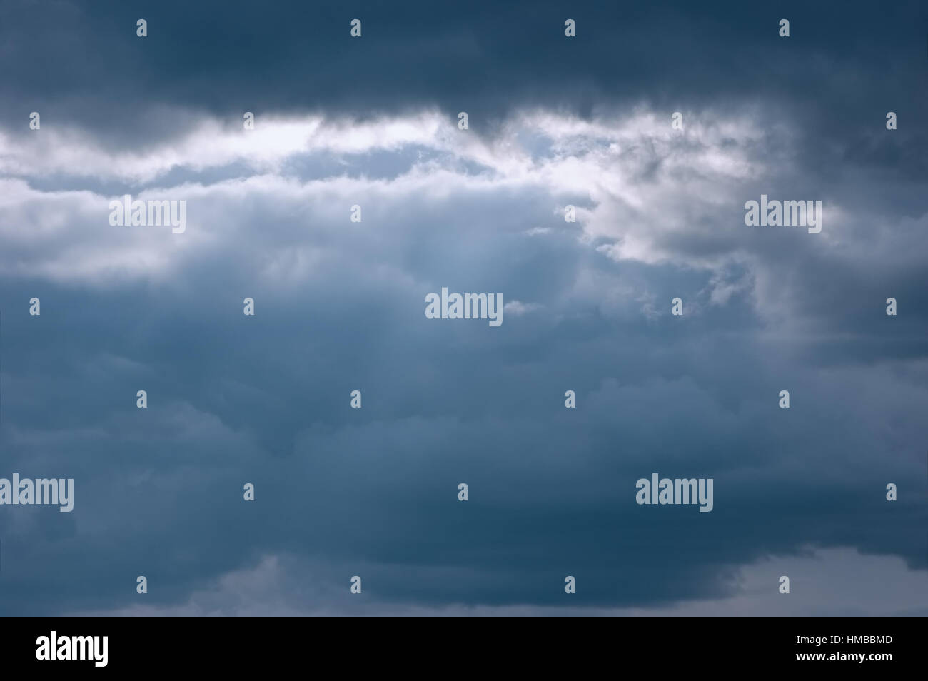 Moody mar cloudscape, leves rayos de sol, nubes azul oscuro, gran fondo de cielo horizontal Foto de stock