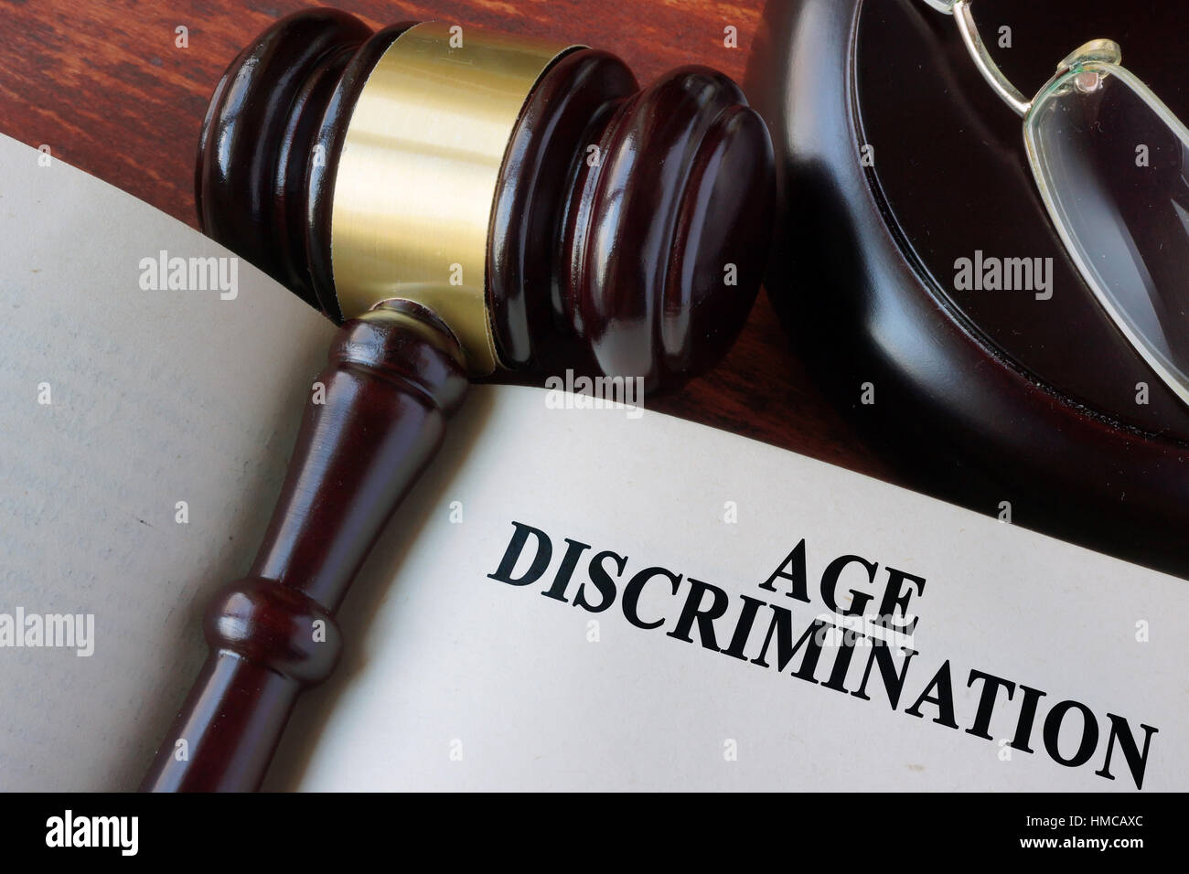 Libro con el capítulo de discriminación por motivos de edad y un martillo. Foto de stock