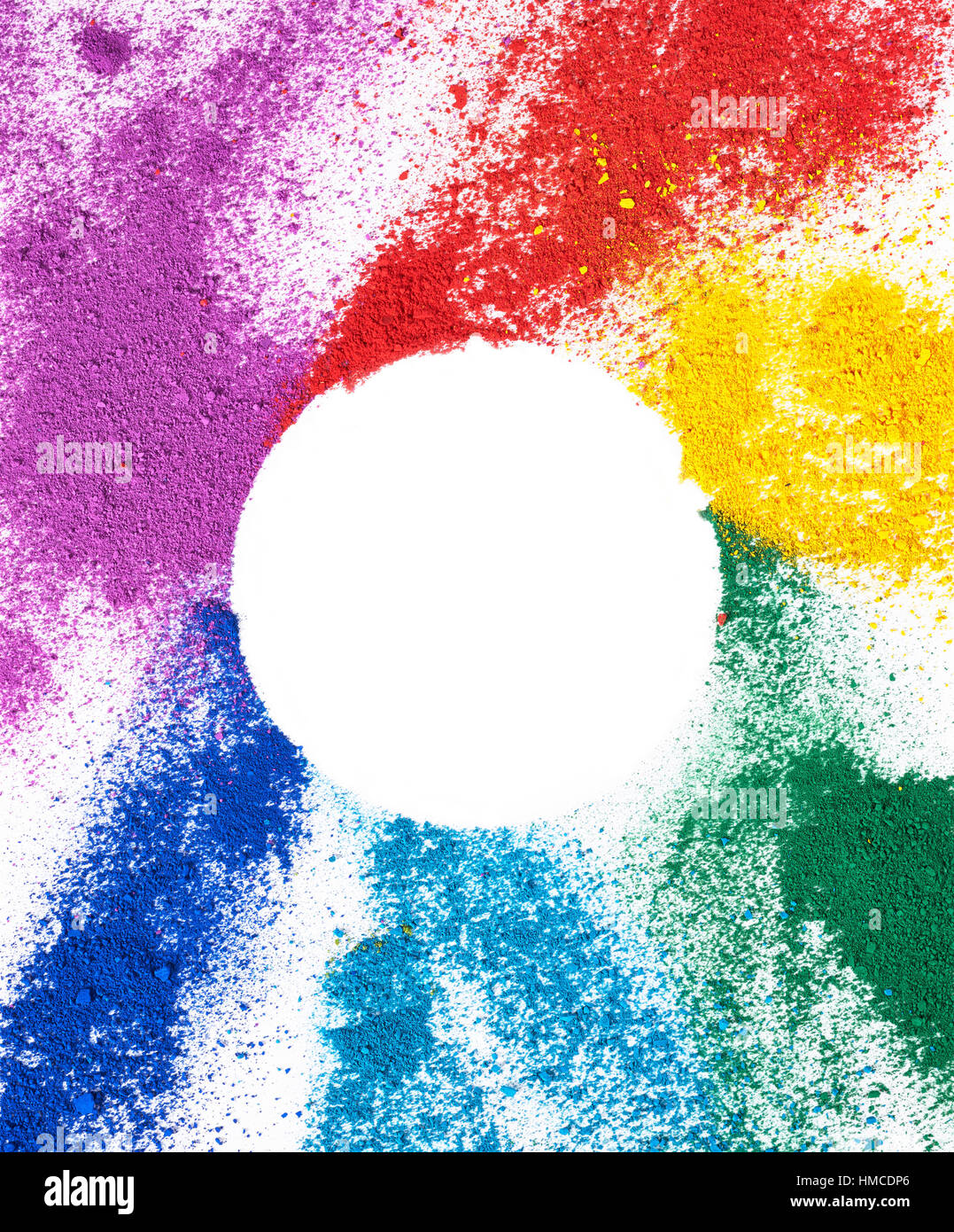 Polvos de colores brillantes sobre un fondo completamente blanco con un círculo blanco en el centro de la imagen. Foto de stock