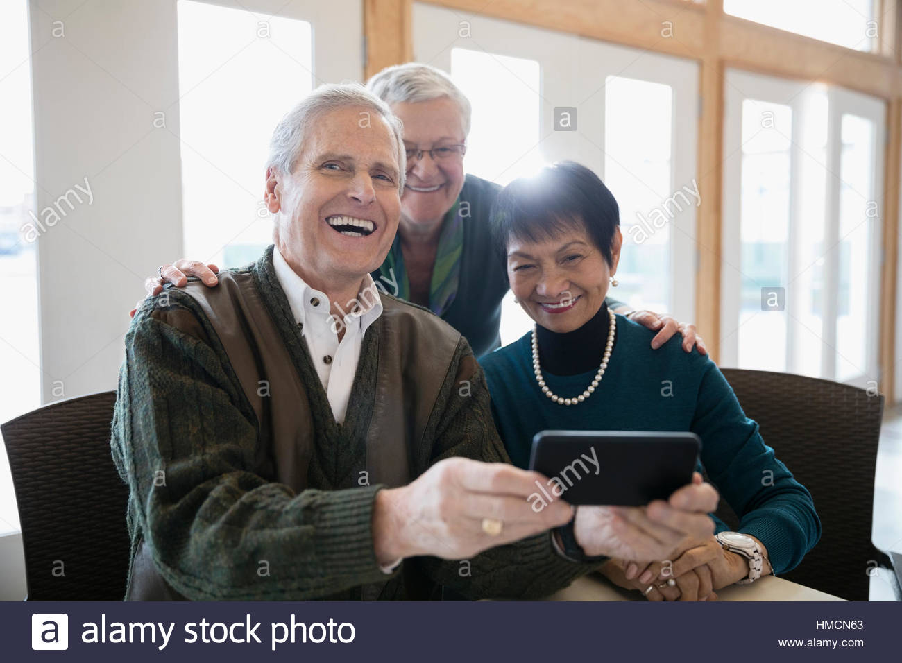 Retrato sonriente adulto senior amigos utilizando el teléfono inteligente. Foto de stock
