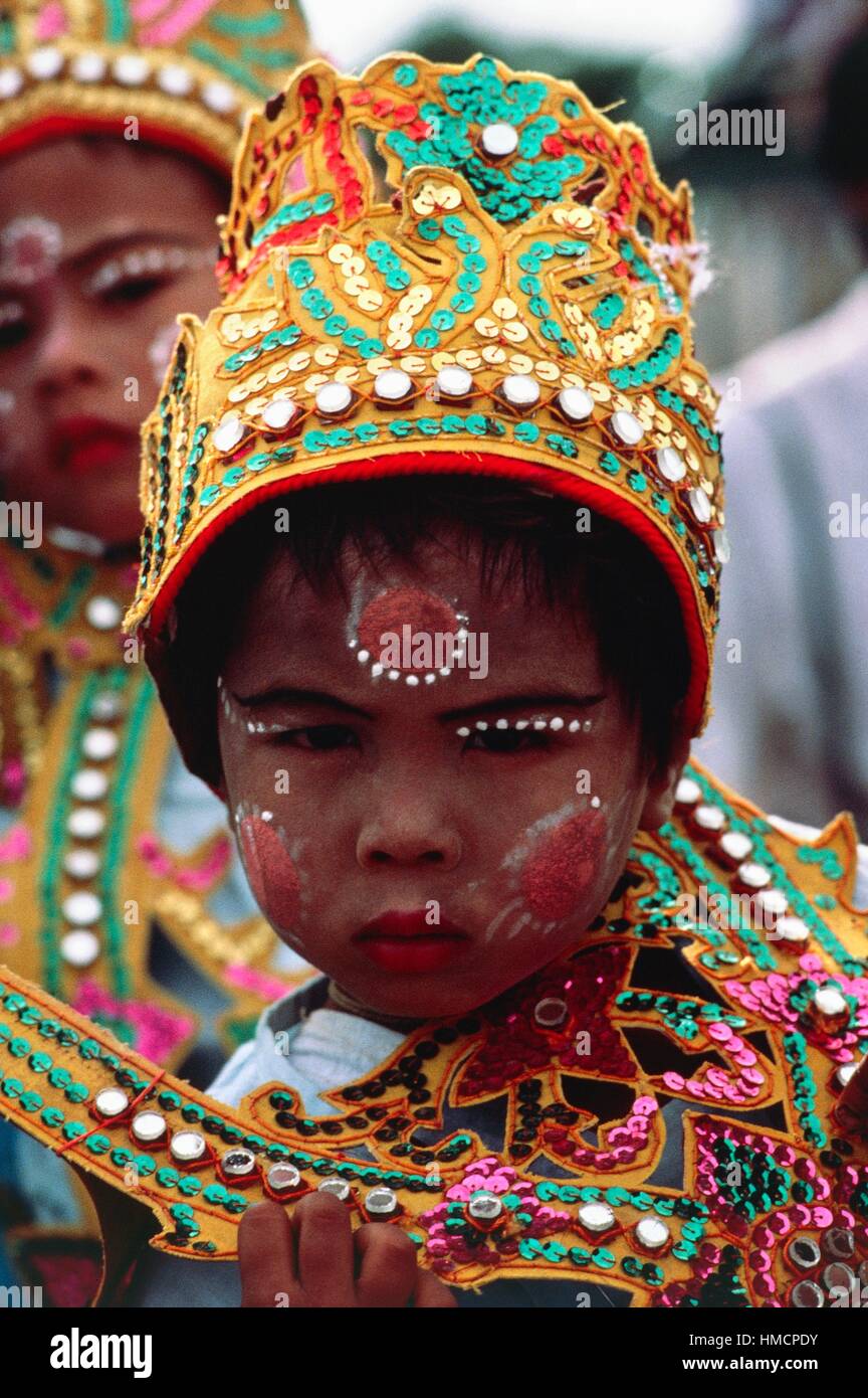 Niño con cara pintada y decorada vistiendo ropas tradicionales durante la ceremonia shinpyu novitiation ceremonia budista Foto de stock