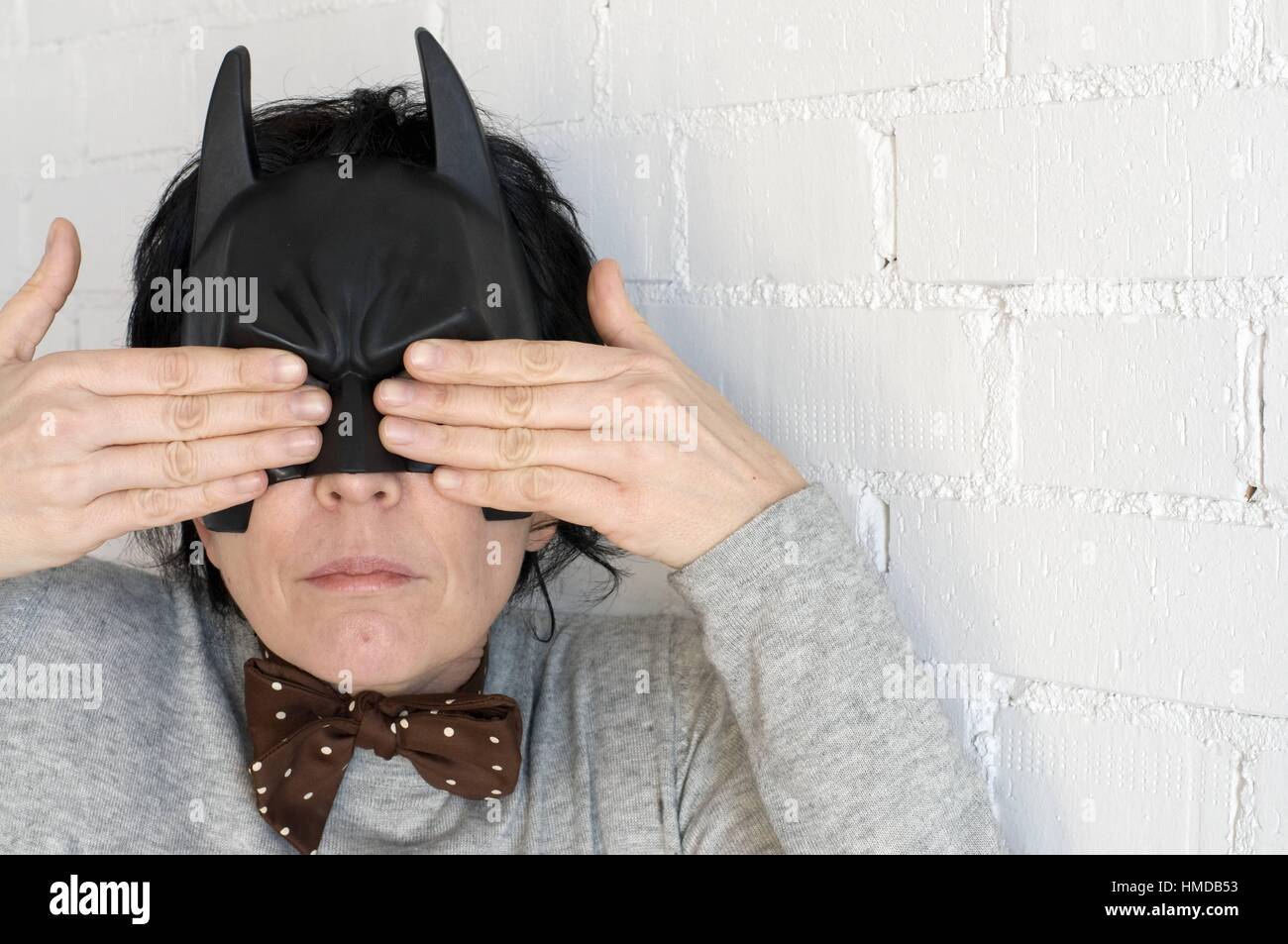 Mujer joven con una máscara de Batman y la expresión de una niña notty y  con las manos sobre sus ojos Fotografía de stock - Alamy