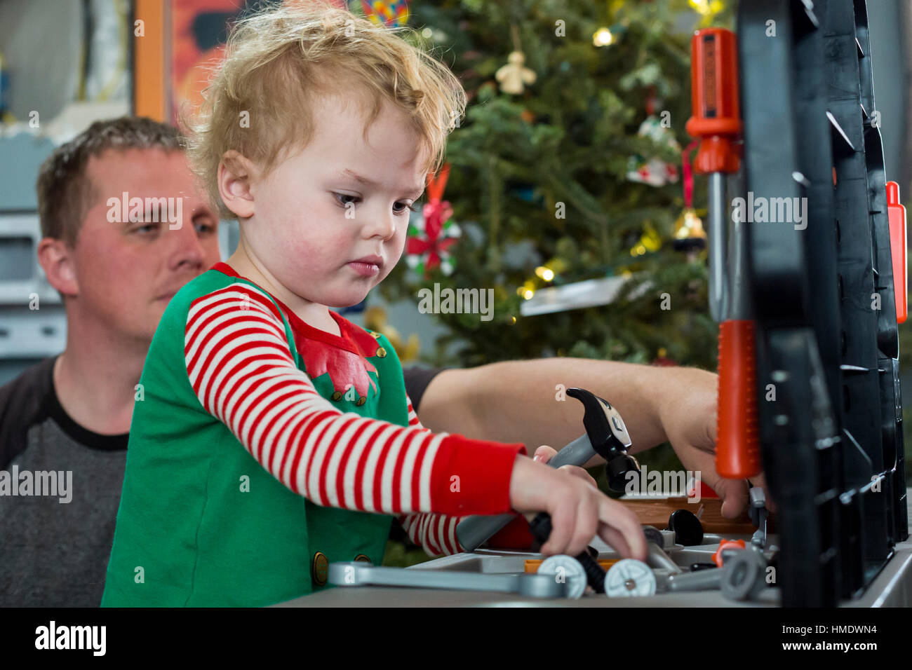 Denver, Colorado - Adam Hjermstad Jr., 2 1/2, juega con un conjunto de herramientas que él consiguió para la Navidad como su papá, Adam Hjermstad Sor, relojes. Foto de stock
