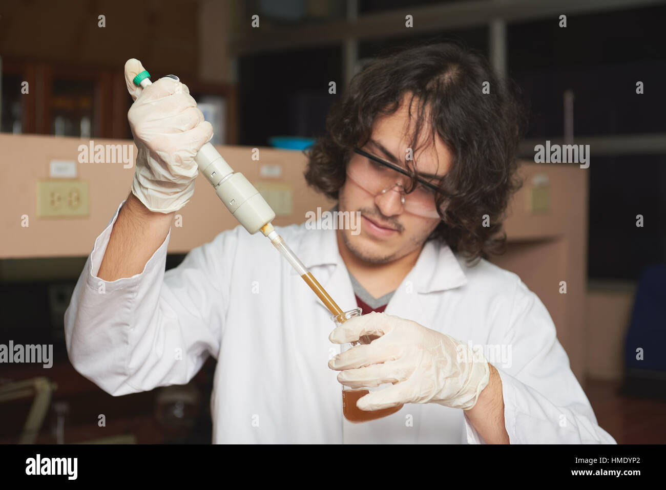 El biólogo joven tomar brown muestra de agua sucia en el laboratorio Foto de stock