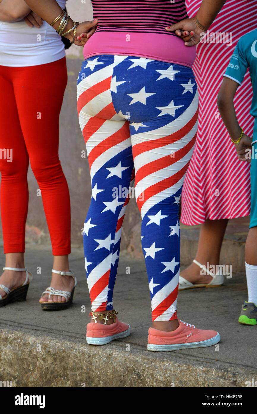 Mujer vistiendo pantalones diseñados con los colores de la bandera de la U. caminando en una calle de Trinidad, Cuba. Foto de stock