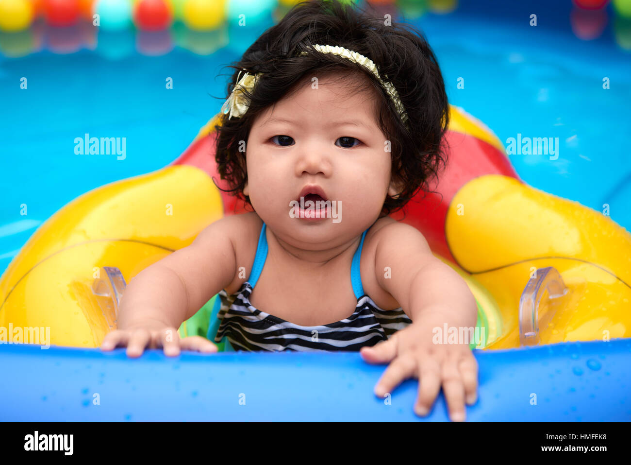 Niña asiática en bañador y flotador nadar en piscina con bolas Fotografía  de stock - Alamy