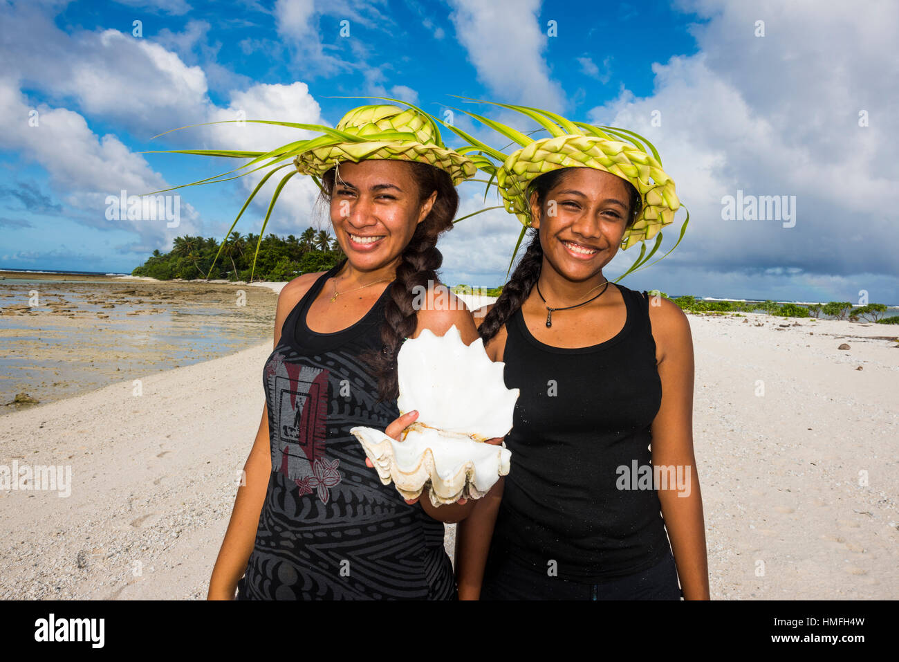 Las niñas locales con hojas de palmera sombreros posando en la laguna de Wallis, Wallis y Futuna, Pacific Foto de stock