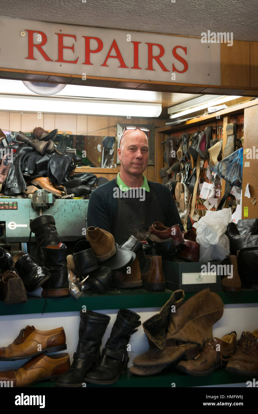 Una antigua zapatería / zapatero corrige los zapatos en su concurrida