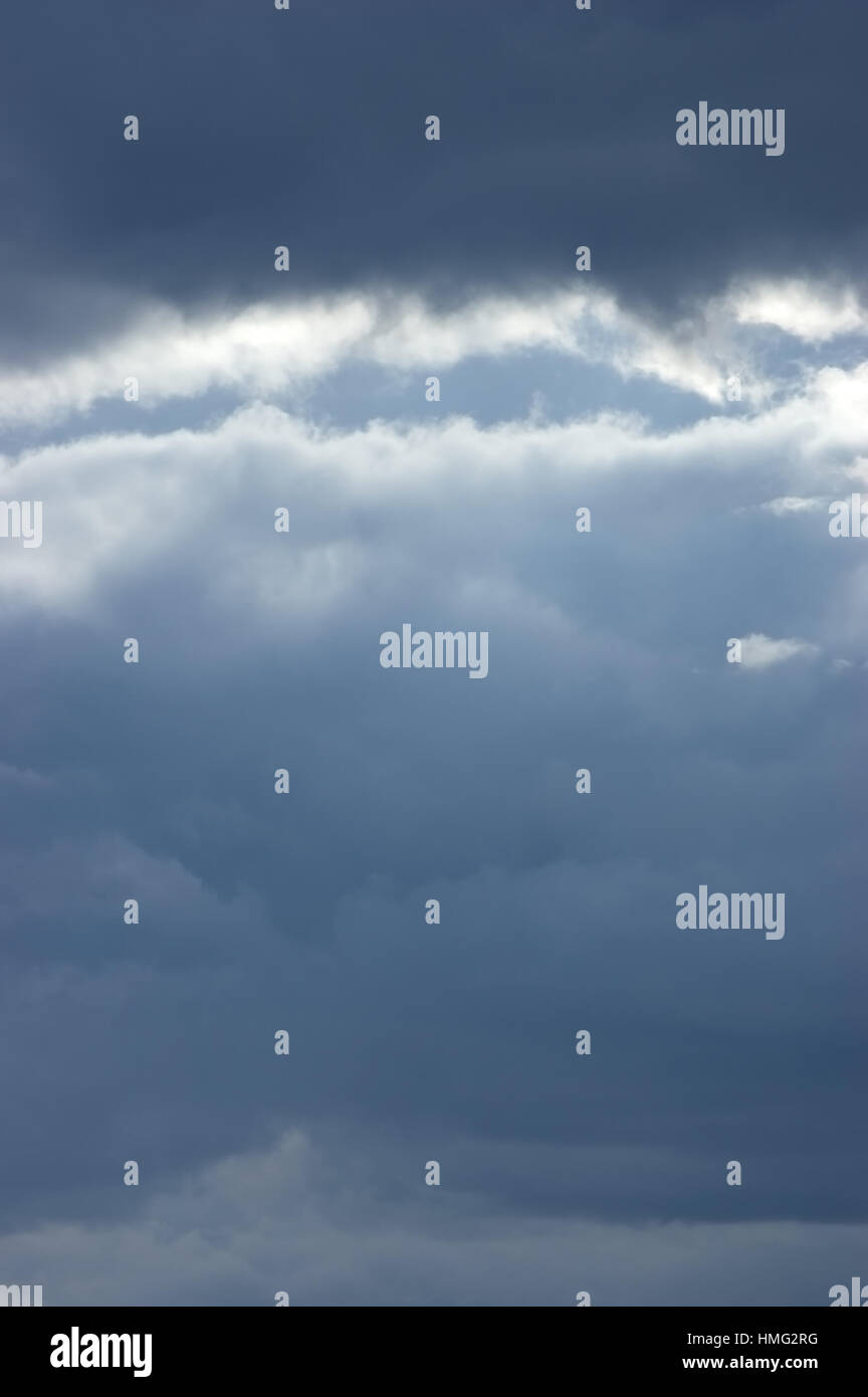 Moody mar cloudscape leves rayos de sol verticales nubes azul oscuro fondo del cielo Foto de stock