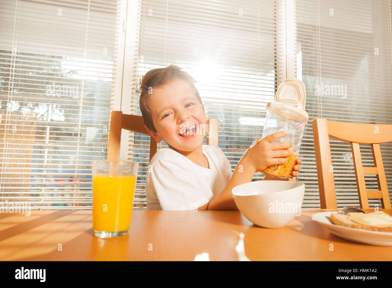 Un chico pequeño y lindo haciendo el desayuno en la soleada mañana Foto de stock