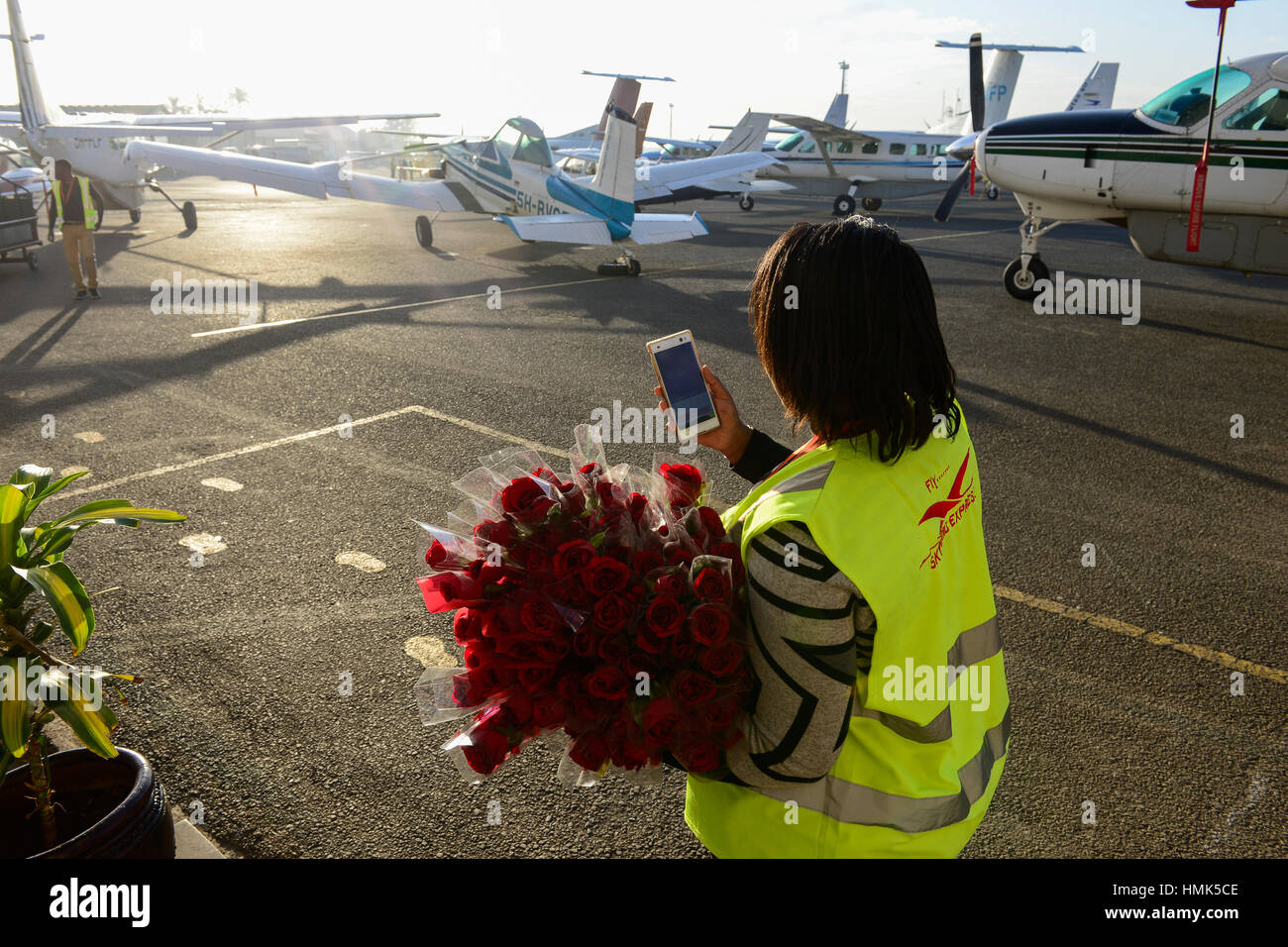 KENYA, Nairobi, el aeropuerto Wilson, empleado del servicio de aviones hacia el cielo express presenta rosas a los pasajeros por día Valentins Foto de stock