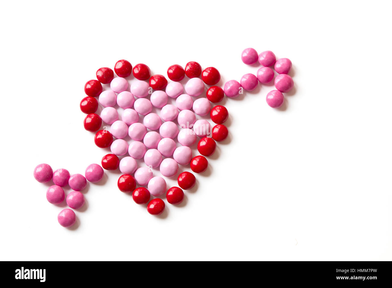 Colorido caramelo rojo y rosa en forma de un corazón con una flecha aislado sobre un fondo blanco. Foto de stock