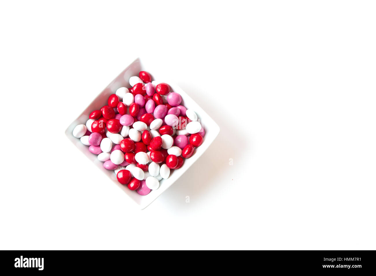 Colores rojo, blanco, rosa recubierto de dulces de San Valentín en un recipiente aislado sobre fondo blanco con espacio para copiar el espacio Foto de stock