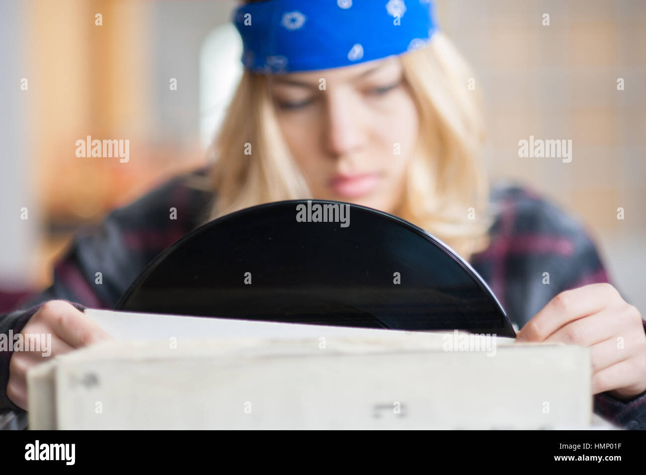 Bastante joven mujer rubia mirando a grabar música de muchos otros en el estante, se centran en vinilo negro Foto de stock