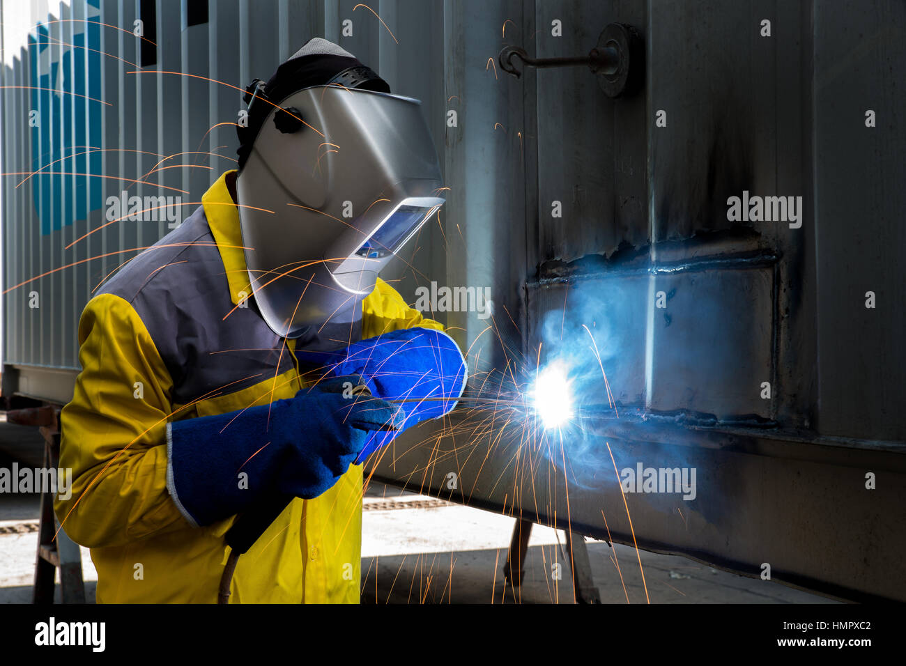 Trabajador de la industria del acero con soldadura de reparación de estructuras de contenedor taller de fabricación en la industria de fábrica. Foto de stock