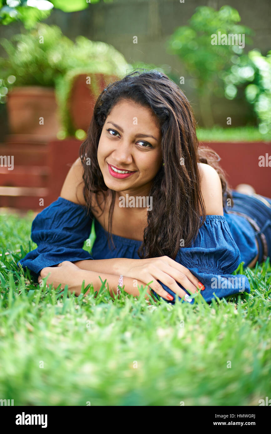 Adolescente chica hispana recostada sobre la hierba del parque Foto de stock