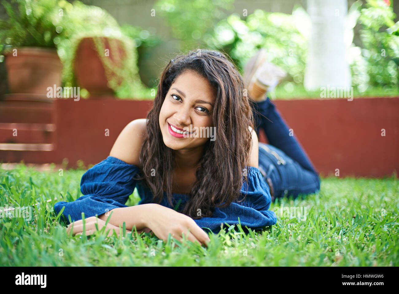 Adolescente latino chica recostada sobre la hierba verde de estacionamiento Foto de stock
