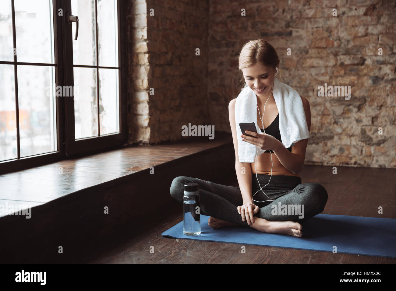 Ajuste a la mujer con auriculares y dispositivo móvil escuchando música en  la máquina de correr en el gimnasio Fotografía de stock - Alamy