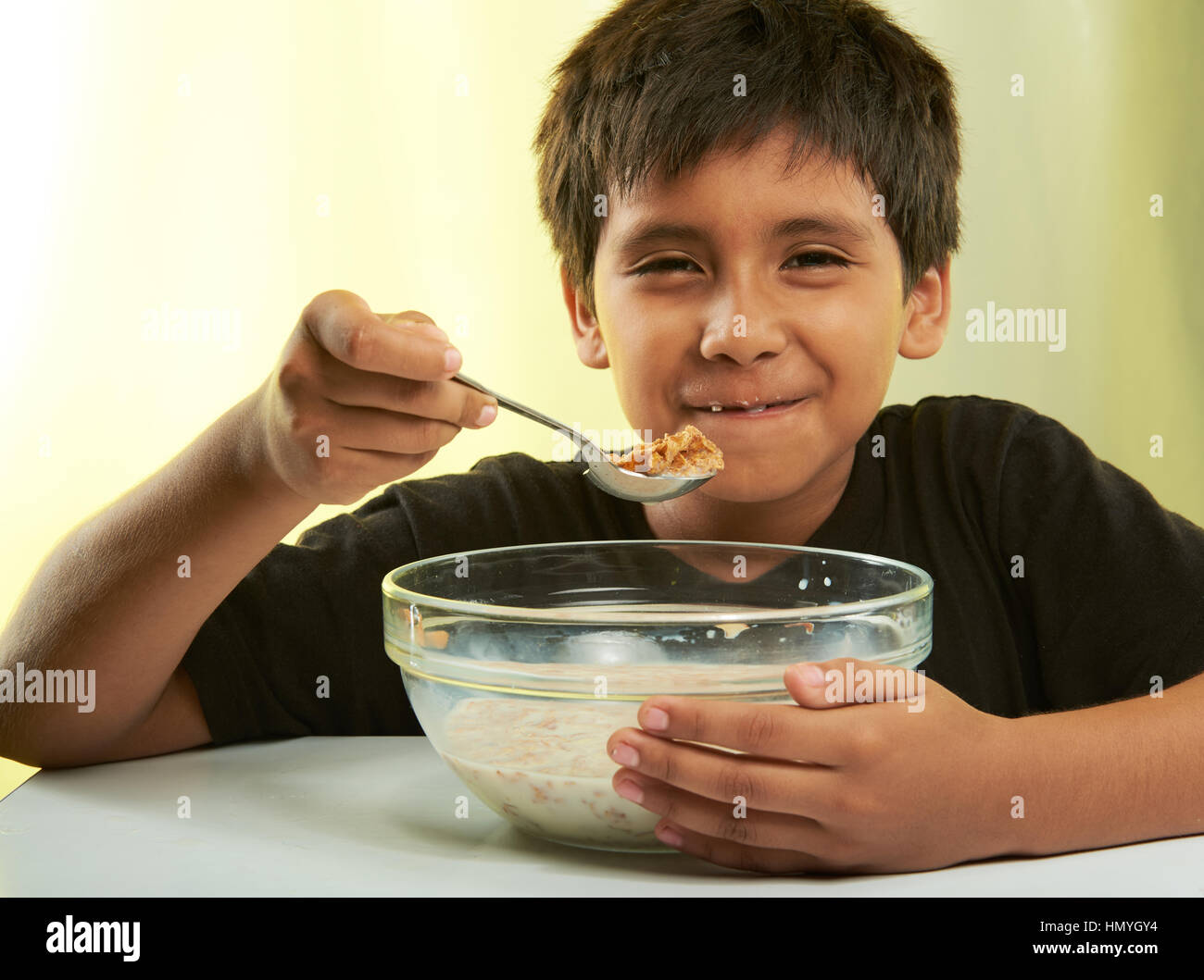 Boy mantenga cuchara con cereal aislado en amarillo Foto de stock