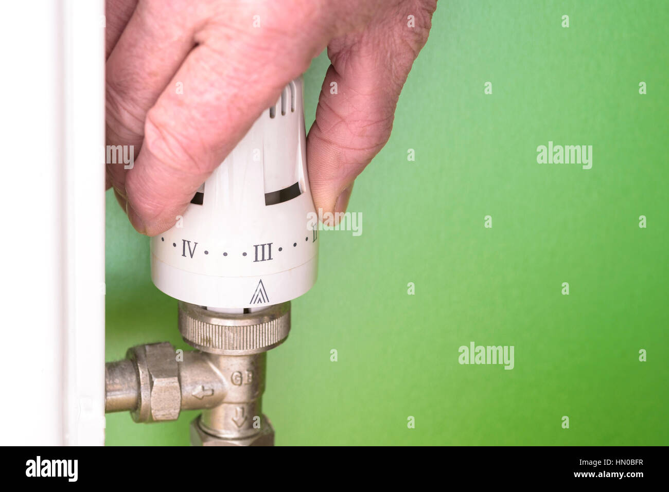 Hombre regular un radiador válvula thermost.bajar la calefacción para ahorrar energía. Foto de stock