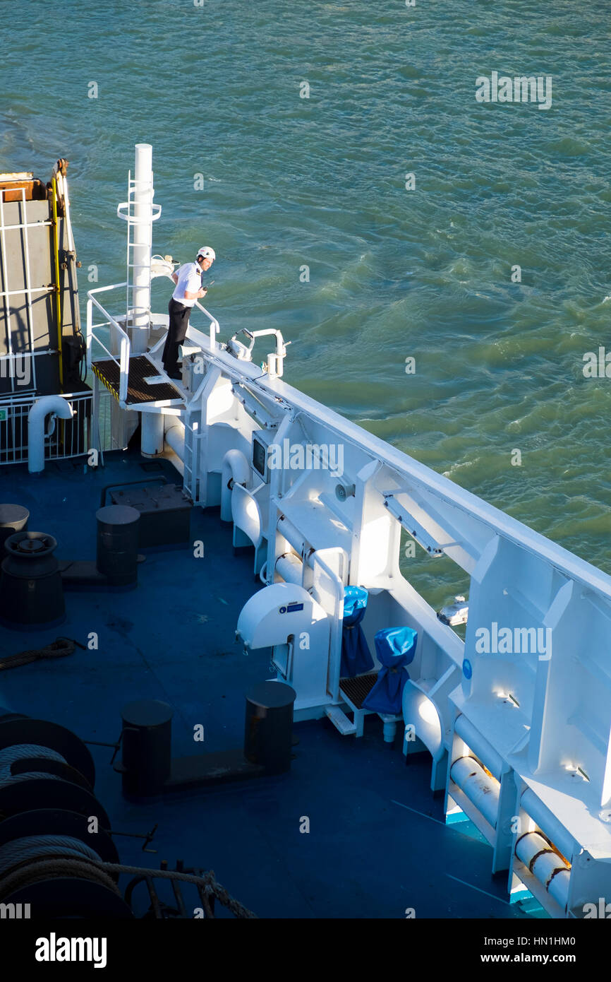 Miembro de la tripulación del ferry comprobación de la holgura al costado del barco partiendo del puerto Foto de stock