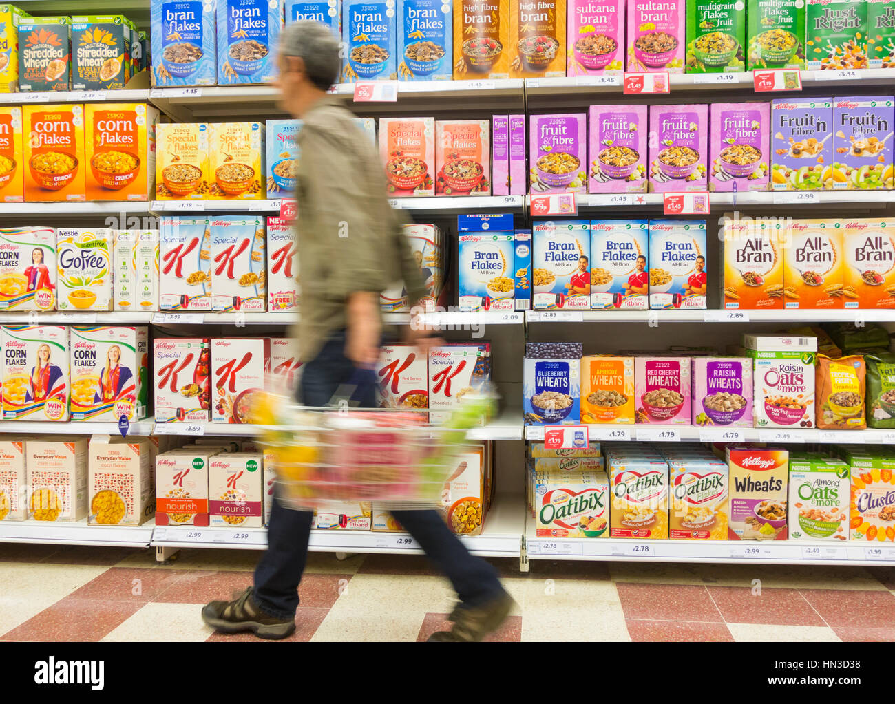 Hombre maduro, llevando la cesta caminando por los cereales de desayuno en el supermercado Tesco. UK Foto de stock