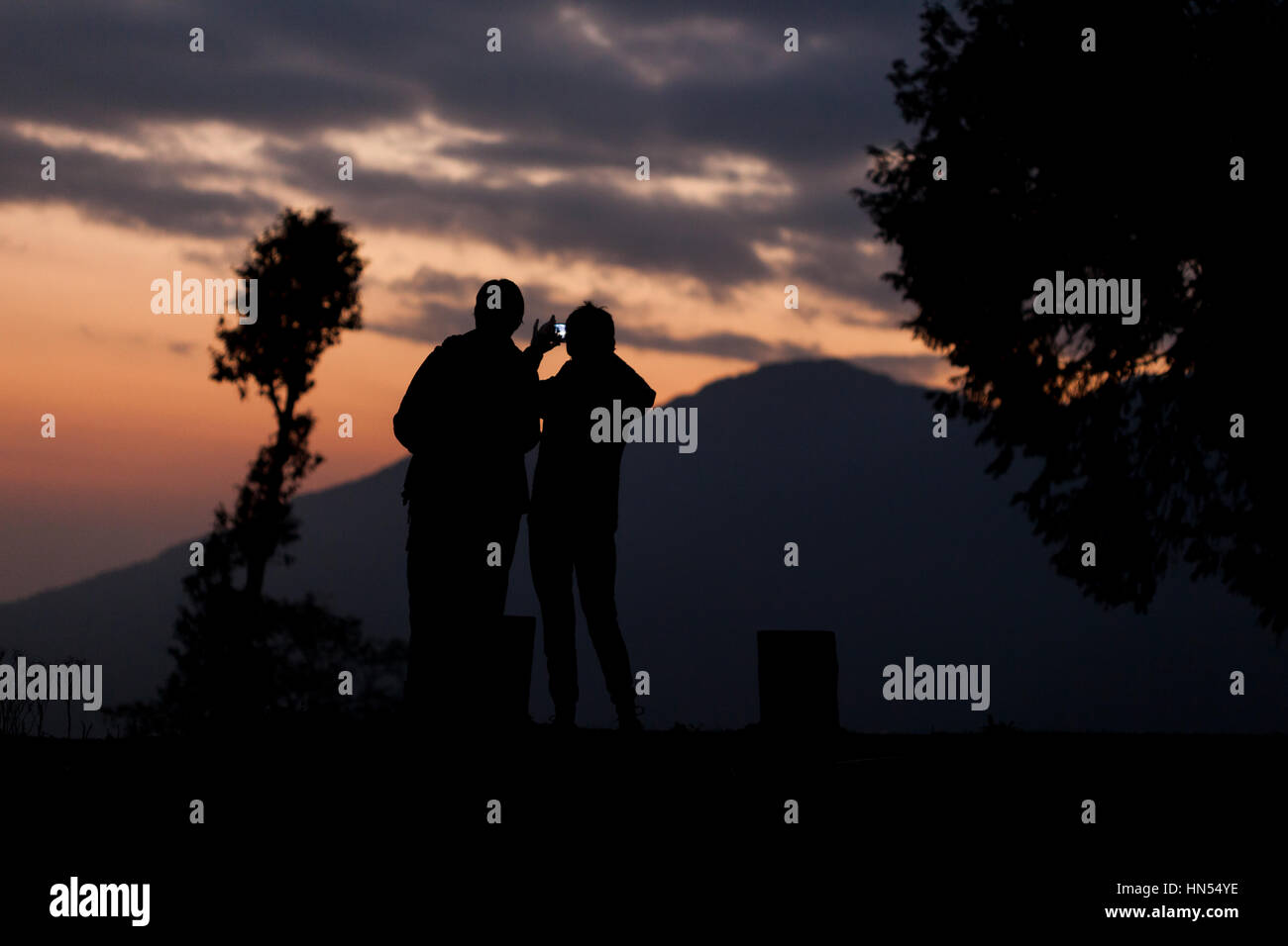 Dos senderistas tomar una fotografía con su smartphone en las montañas al atardecer Foto de stock