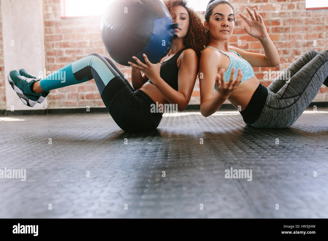 Dos mujeres deportistas entrenamiento con balón medicinal en el gimnasio. Las niñas que trabajan fuera para dar forma a su cuerpo. Foto de stock