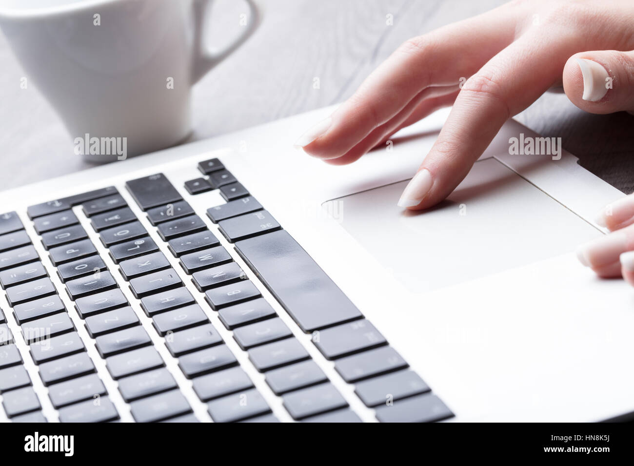 La empresaria navegando por internet en un ordenador portátil con una vista de cerca de los dedos y la superficie táctil Foto de stock